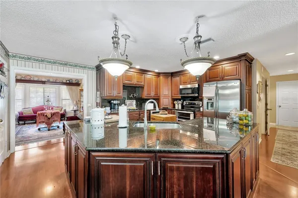 a kitchen with stainless steel appliances granite countertop a sink a stove and chairs