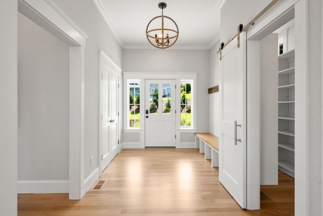 a view of a hallway with wooden floor and a chandelier