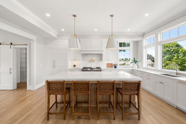 a kitchen with kitchen island stainless steel appliances a dining table chairs sink and wooden floor