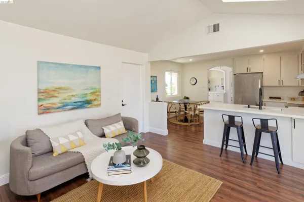 a living room with furniture kitchen view and a wooden floor