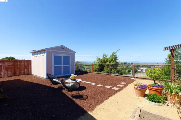 a view of a backyard with table and chairs potted plants and a floor to ceiling window