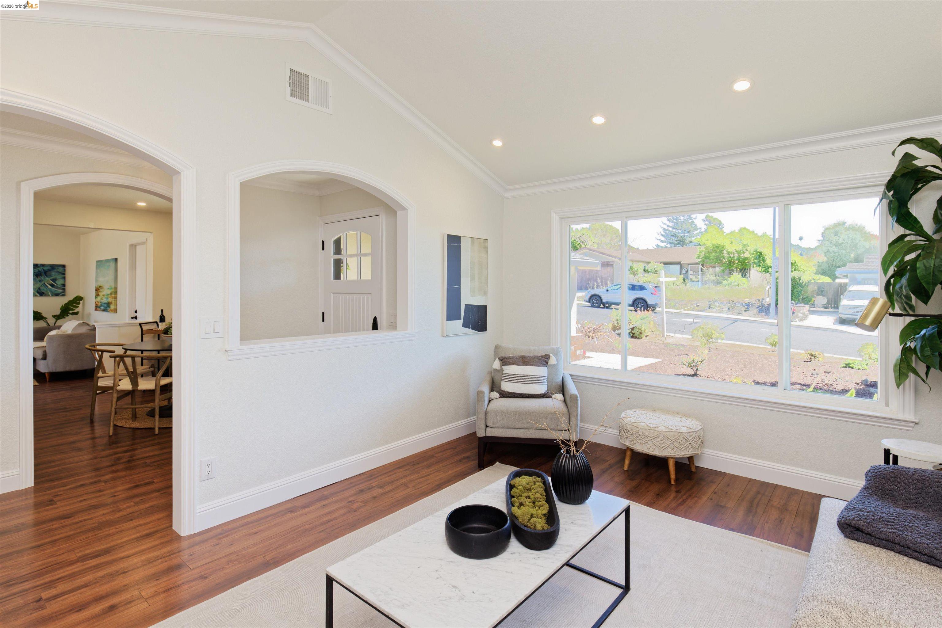 983 Seascape Circle Rodeo, CA 94572 - Photo 8 of 45 Living area featuring lofted ceiling, dark wood-style floors, arched walkways, recessed lighting, and crown molding