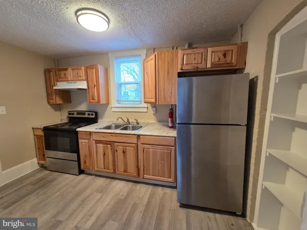 a kitchen with granite countertop a refrigerator a sink and a stove top oven