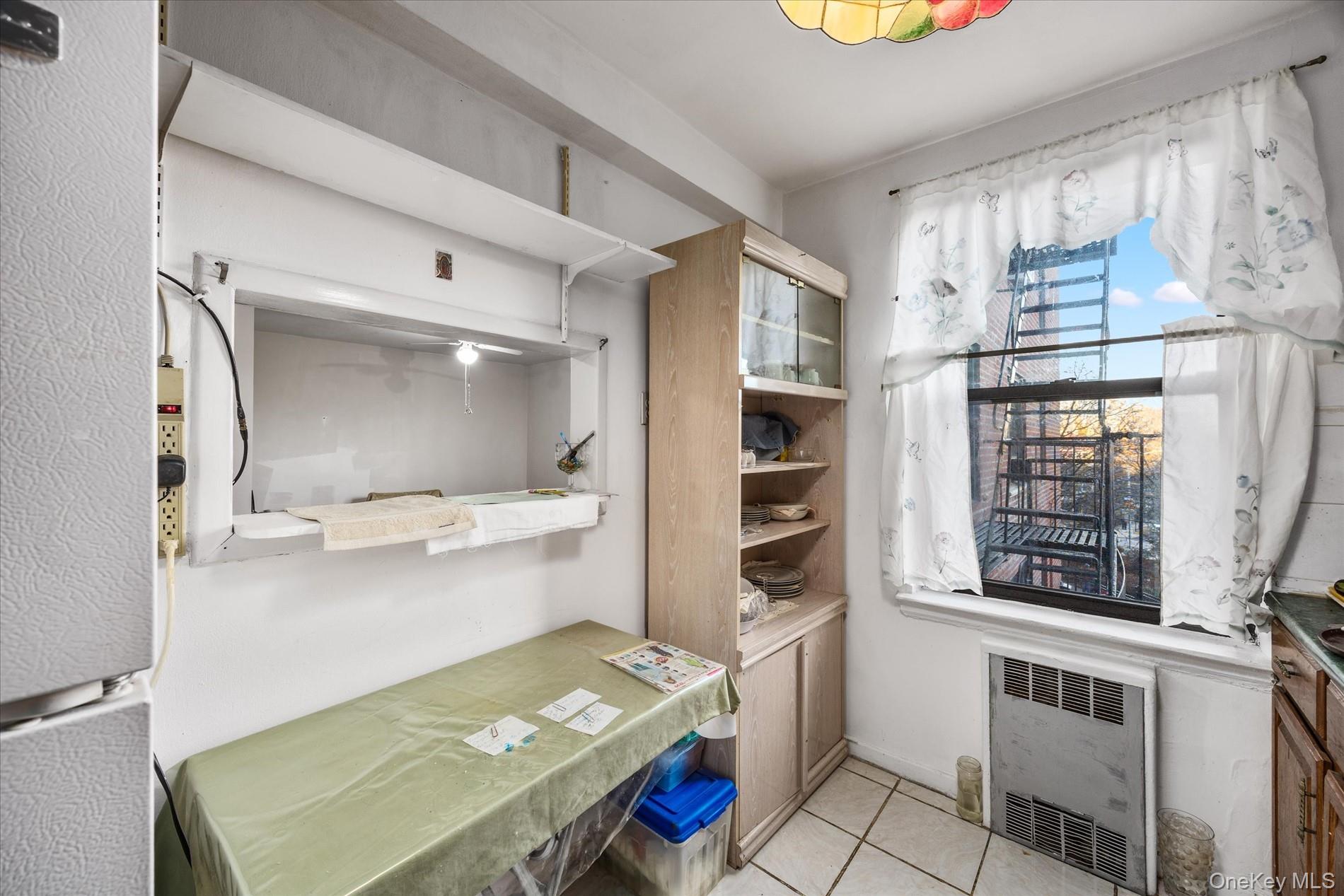 52-35 39th Road, Unit 2C Queens, NY 11377 - Photo 7 of 10 Kitchen with freestanding refrigerator, light tile patterned floors, and radiator