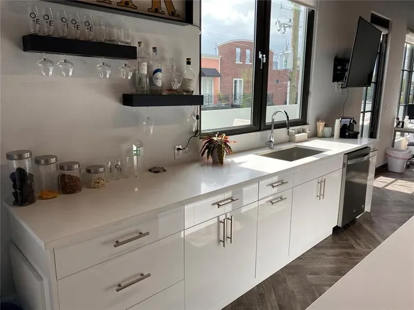 a kitchen with a sink dishwasher and white cabinets with wooden floor
