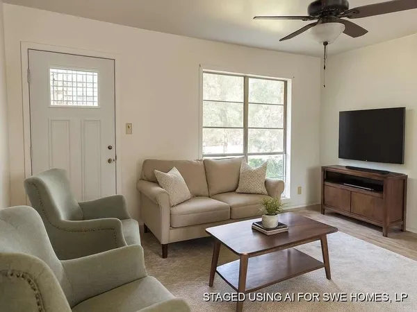 a living room with furniture a flat screen tv and a window