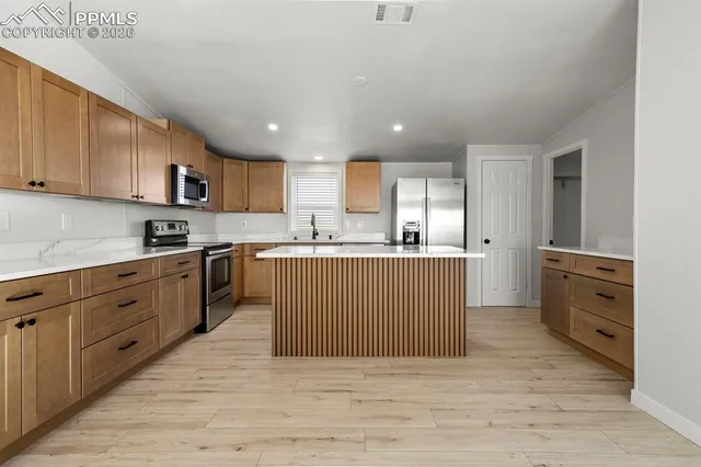 a large kitchen with stainless steel appliances granite countertop a stove a sink dishwasher and a refrigerator