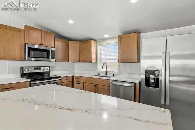 a kitchen with stainless steel appliances granite countertop a sink a stove top oven a refrigerator and a granite counter tops