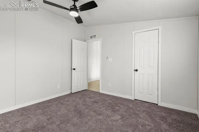 a view of a livingroom with a ceiling fan & cabinets