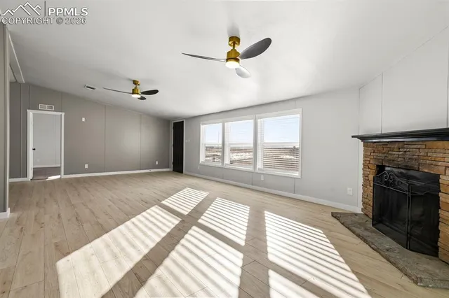 a view of an empty room with a fireplace and a window