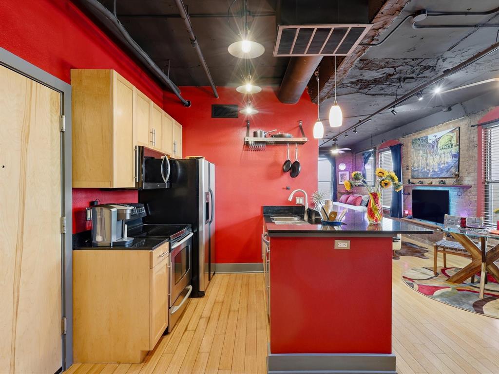 910 Houston Street, Unit 305 Fort Worth, TX 76102 - Photo 5 of 22 a kitchen with stainless steel appliances kitchen island granite countertop a table chairs in it and wooden floors