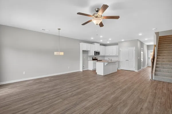 a view of an empty room with kitchen appliances and a ceiling fan