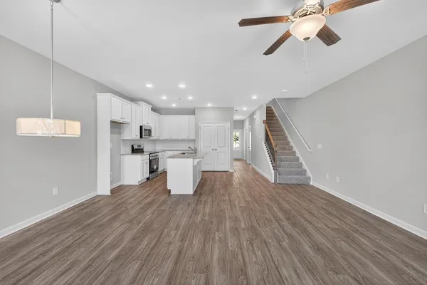 a view of an empty room and window a ceiling fan and wooden floor
