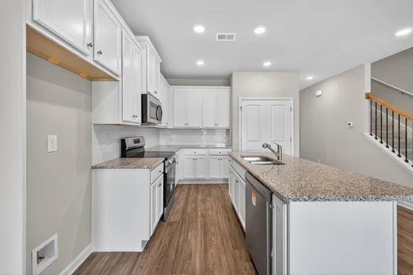 a kitchen with stainless steel appliances granite countertop a sink a stove and cabinets