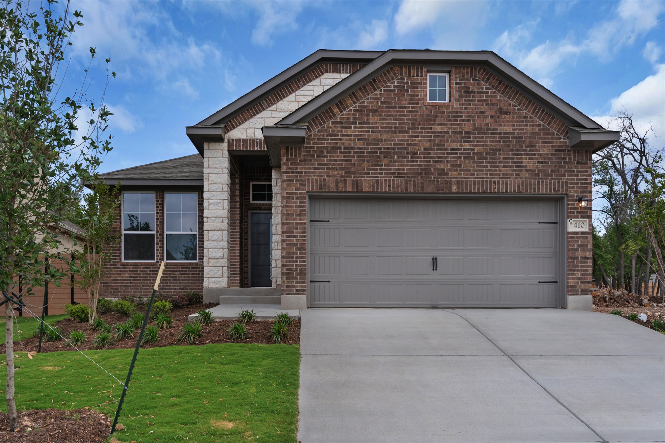 Ranch-style home with brick siding, a garage, driveway, and a front yard