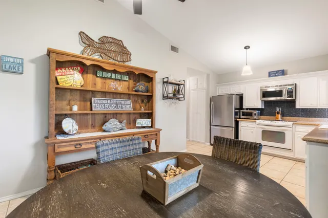 a living room with stainless steel appliances furniture a rug and a kitchen view