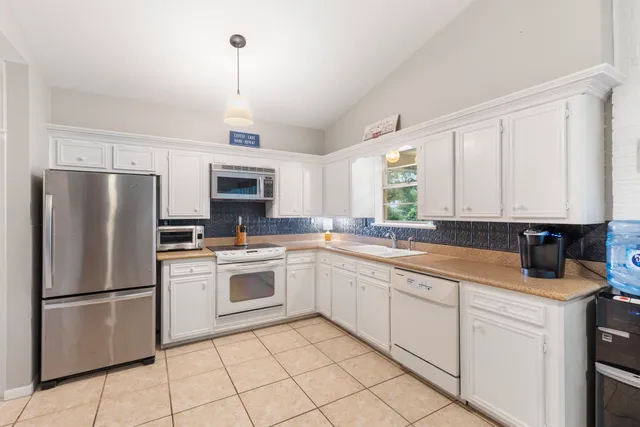 a kitchen with white cabinets stainless steel appliances and a window