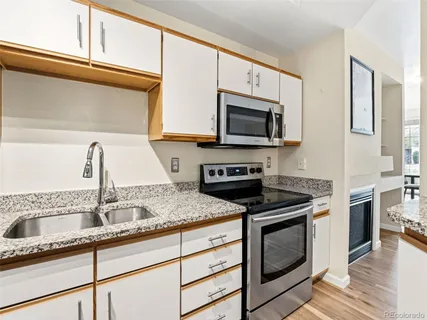 a kitchen with granite countertop a sink cabinets and stainless steel appliances