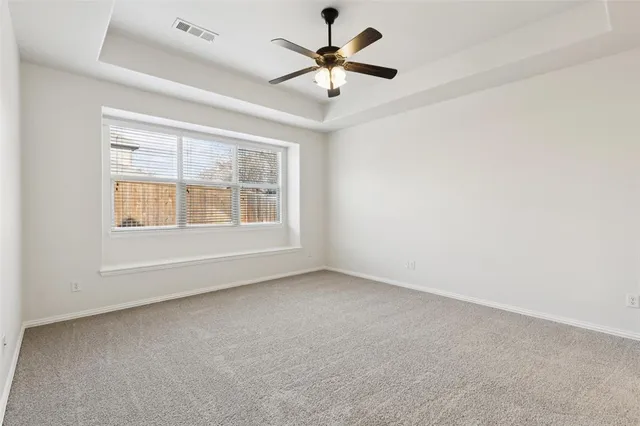 an empty room with chandelier fan and windows