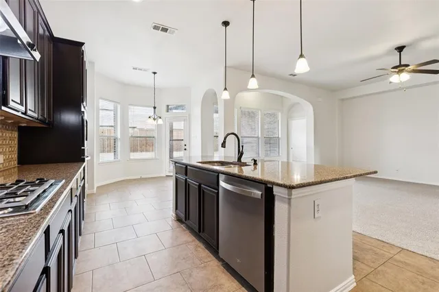 a kitchen with stainless steel appliances granite countertop a sink a stove and a refrigerator