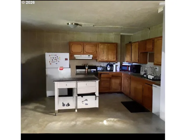 a kitchen with stainless steel appliances a sink a stove a refrigerator cabinets and a window