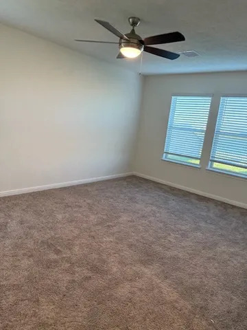 an empty room with windows and fan