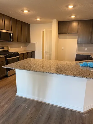 a large kitchen with kitchen island granite countertop wooden cabinets a granite counter tops and a stove