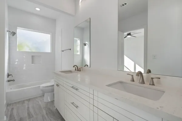 a bathroom with a double vanity sink toilet a shower and a mirror