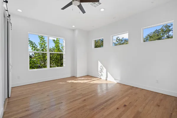 an empty room with wooden floor and windows