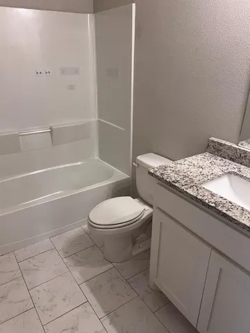 a bathroom with a granite countertop toilet a sink and bathtub