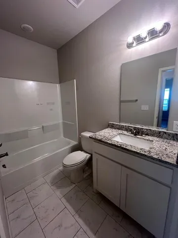 a bathroom with a granite countertop sink a toilet and a bathtub