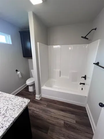 an empty room with wooden floor a ceiling fan and windows