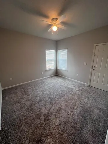 an empty room with windows and fan