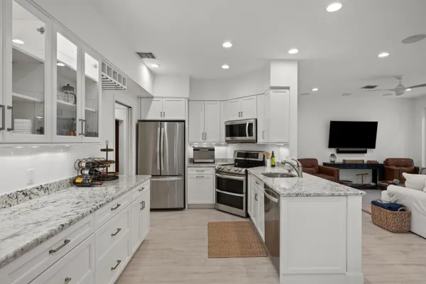 a kitchen with stainless steel appliances kitchen island granite countertop a stove top oven a sink dishwasher a refrigerator and a microwave