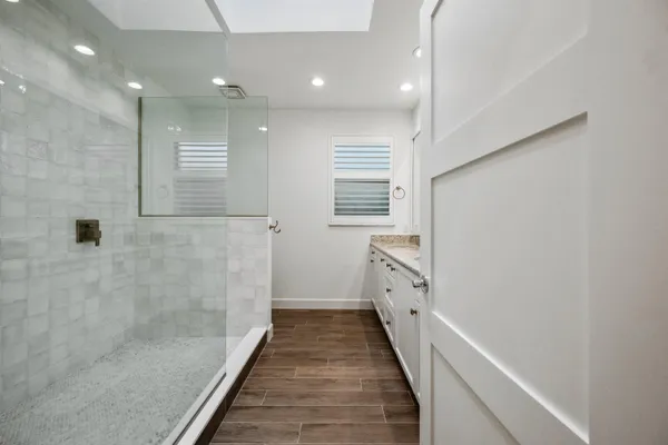 a bathroom with a sink a toilet a shower and a window