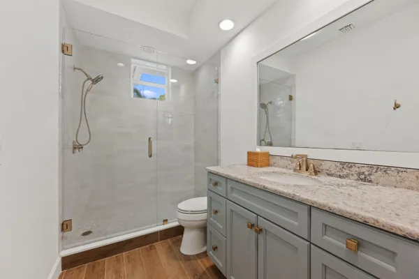 a bathroom with a granite countertop sink a toilet and shower