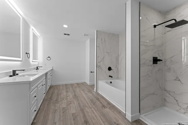 a bathroom with a tub sink shower and two mirror