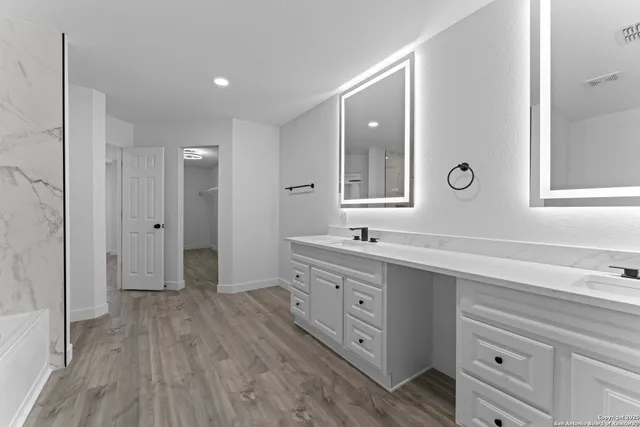 a spacious bathroom with a double vanity sink a mirror and a shower