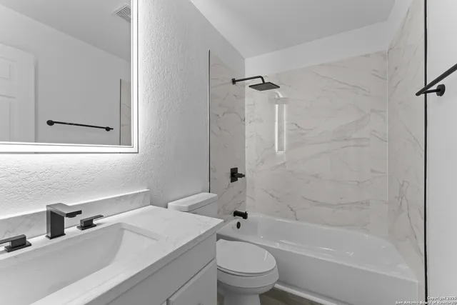 a bathroom with a granite countertop toilet a sink and a bathtub