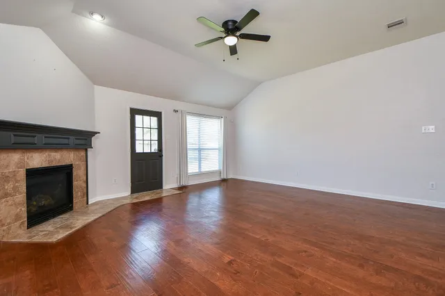 a view of an empty room with window and wooden floor