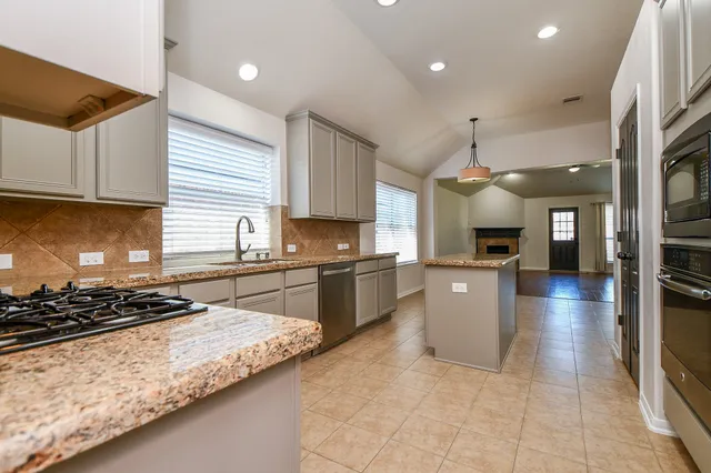 a kitchen with stainless steel appliances granite countertop a stove a sink a refrigerator and a microwave