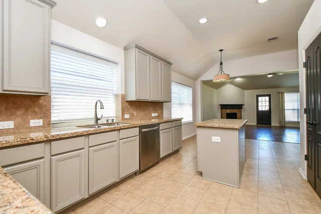 a large kitchen with stainless steel appliances granite countertop a sink and dishwasher a stove top oven with wooden floor