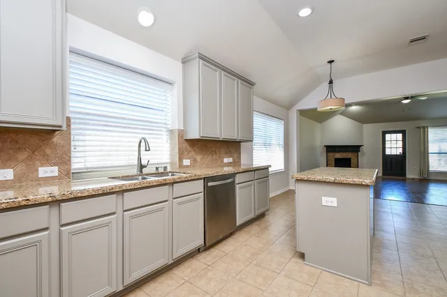 a large kitchen with granite countertop a sink and a stove top oven with wooden floor