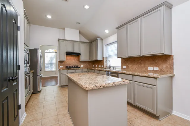 a kitchen with stainless steel appliances granite countertop a stove a sink and a refrigerator