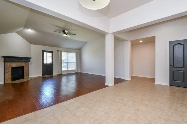 a view of an empty room with window and wooden floor