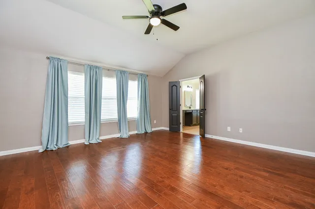 a view of an empty room with window and wooden floor