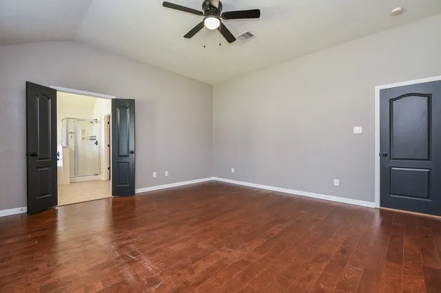 a view of empty room with wooden floor and ceiling fan