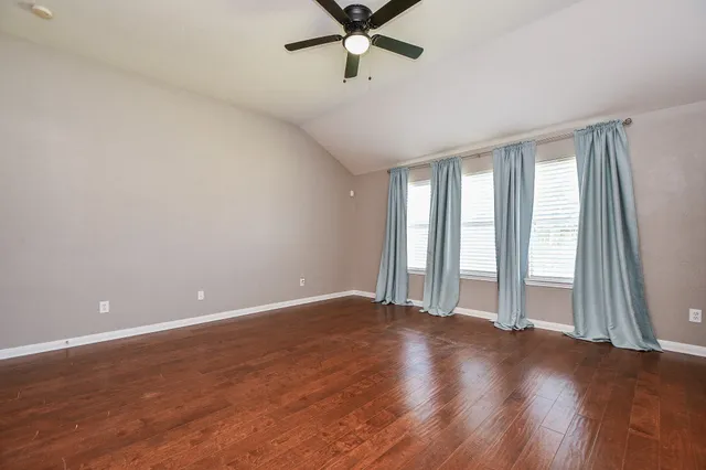 an empty room with wooden floor and windows