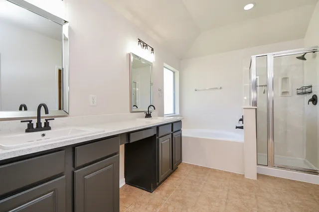 a bathroom with a bathtub sink double vanity and mirror