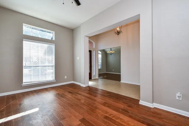 a view of an empty room with wooden floor and a window